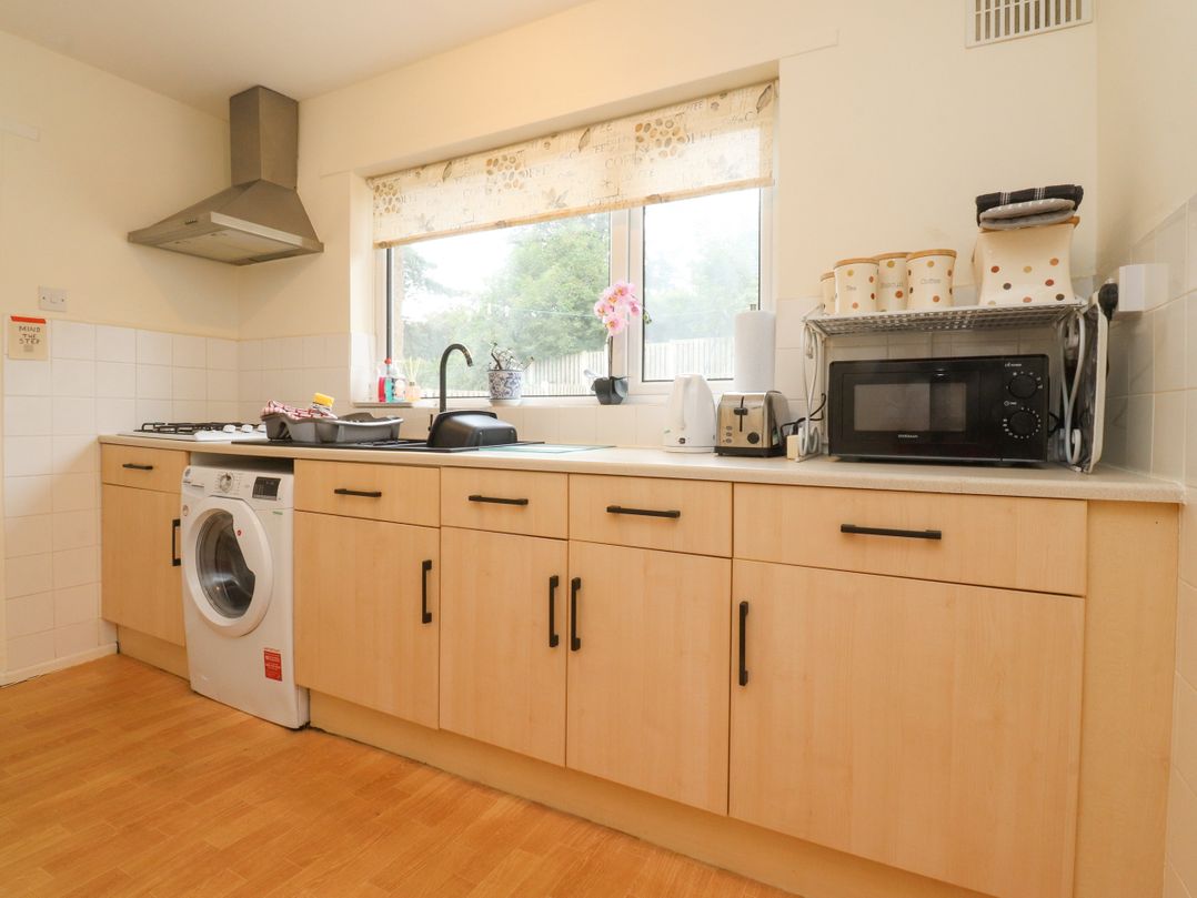 A kitchen with a sink, stove, washing machine and microwave at Wynnville in Embsay near Skipton