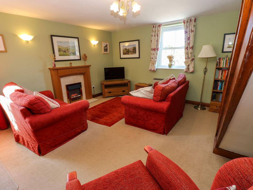A living room with red sofas and a television at Barnbrook Carperby near Leyburn