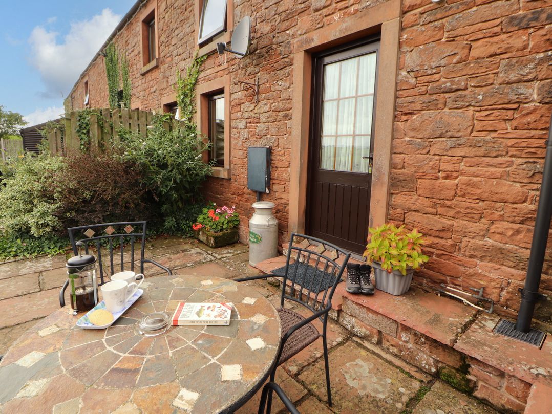 An outdoor seating area with a table and a door at Stable Cottage in Bolton Low Houses