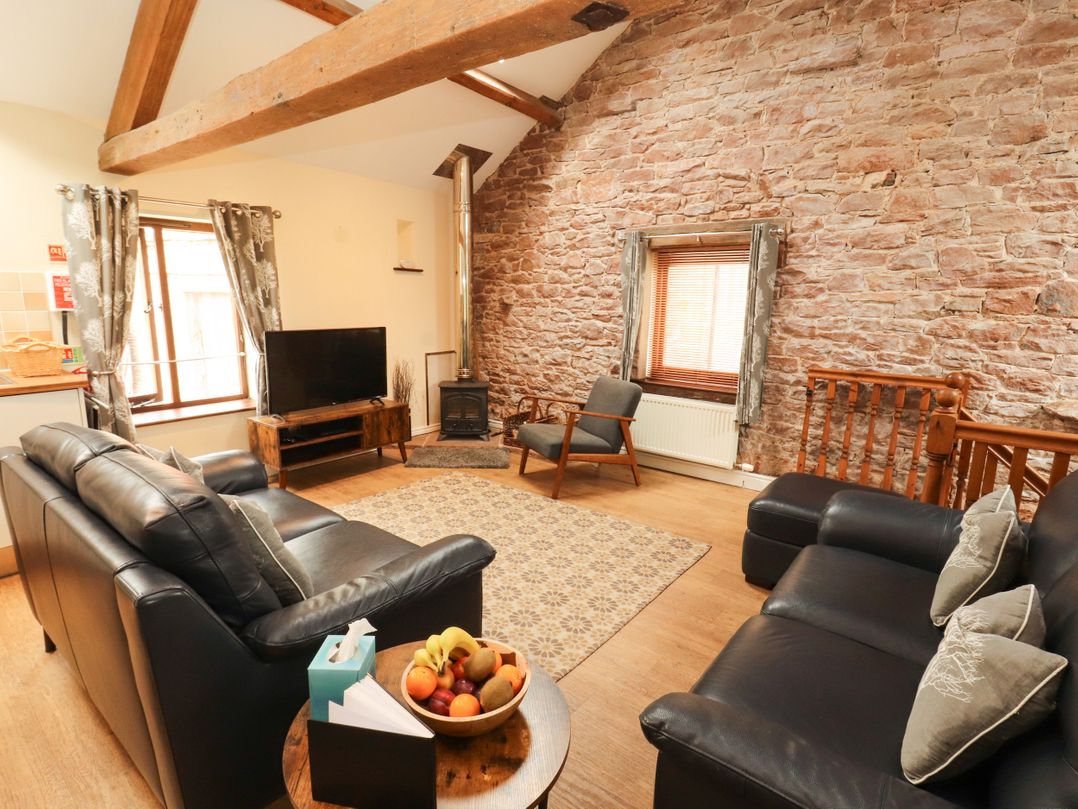 A living room with a sofa, television and wooden beams at Stable Cottage in Bolton Low Houses