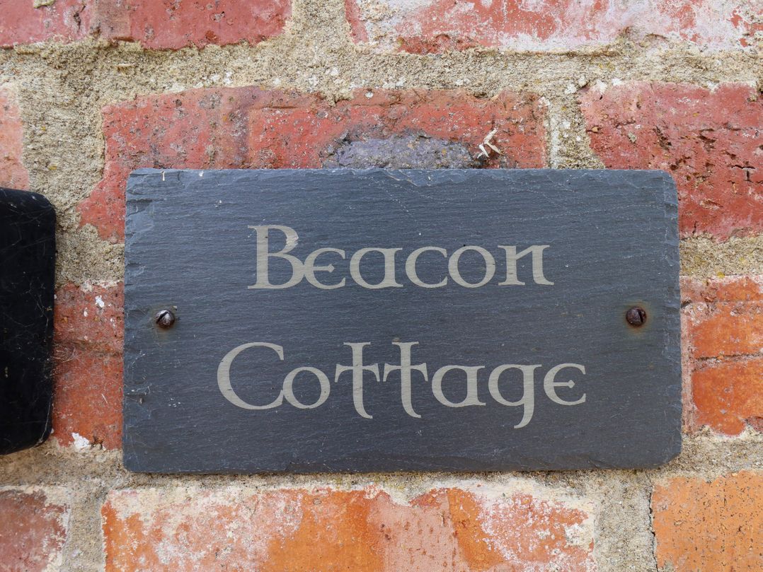 A sign that reads 'Beacon Cottage' attached to a brick wall at Beacon in Gerrick near Moorsholm
