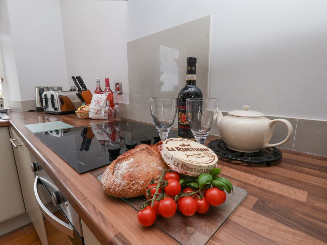 A kitchen with a countertop featuring bread, tomatoes, glasses, and a teapot at Beacon in Gerrick near Moorsholm