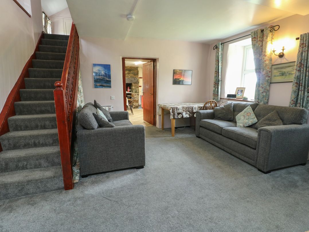 A living room with a staircase, sofas and a table at Glan y Gors in Dinorwic near Llanberis