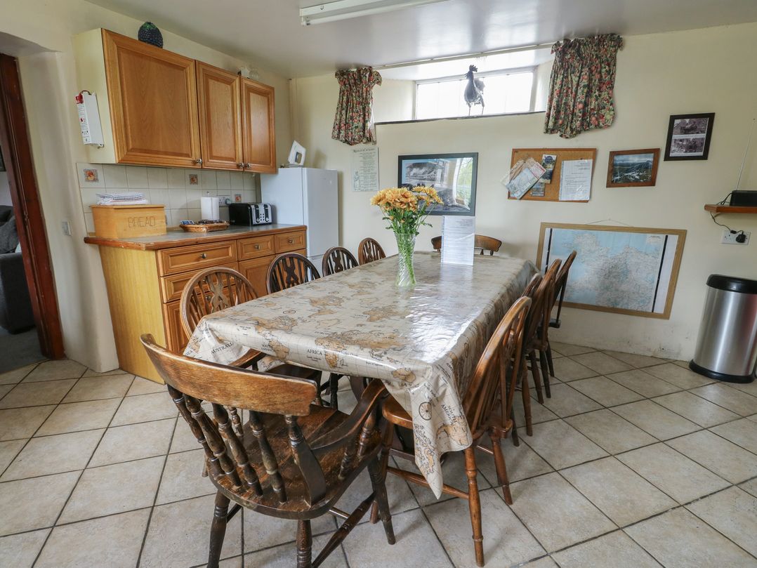 A kitchen with a dining table and cabinets at Glan y Gors in Dinorwic near Llanberis