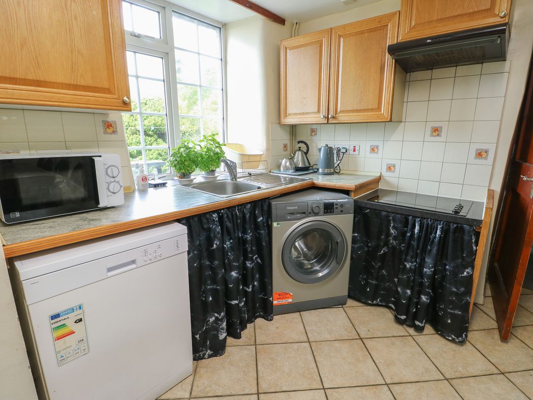 A kitchen with appliances including a microwave, dishwasher, and washing machine at Glan y Gors in Dinorwic near Llanberis