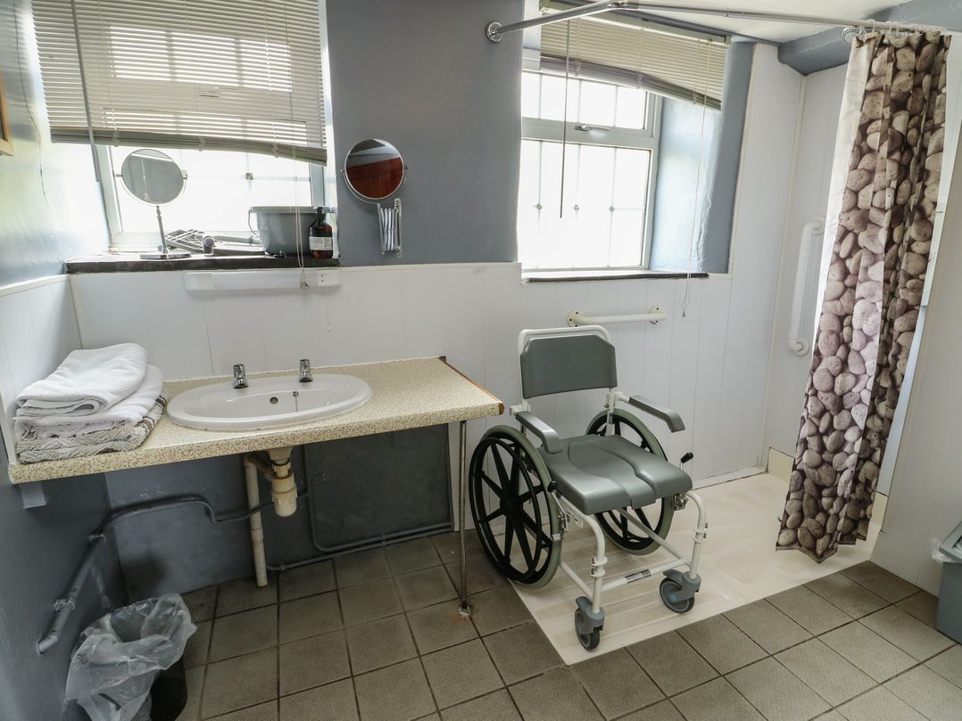 A bathroom with a wheelchair and sink at Glan y Gors Dinorwic near Llanberis