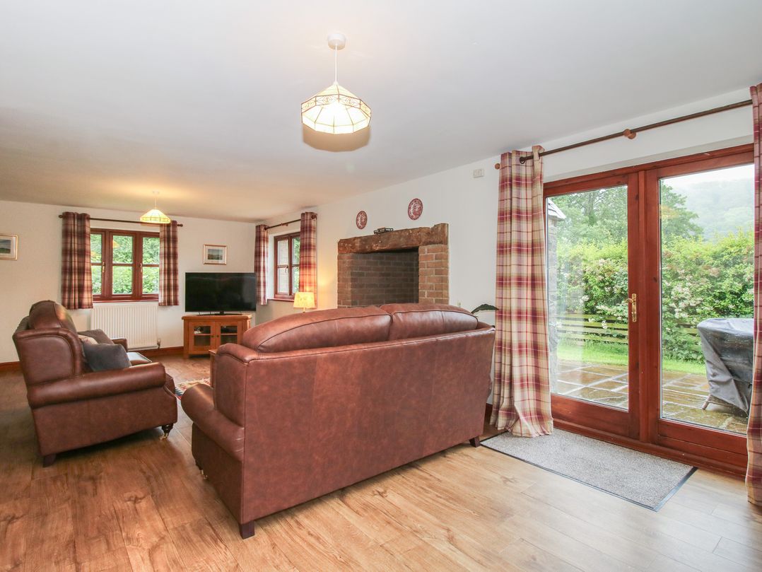 A living room with a sofa and television at Byne Brook Cottage in Strefford near Craven Arms