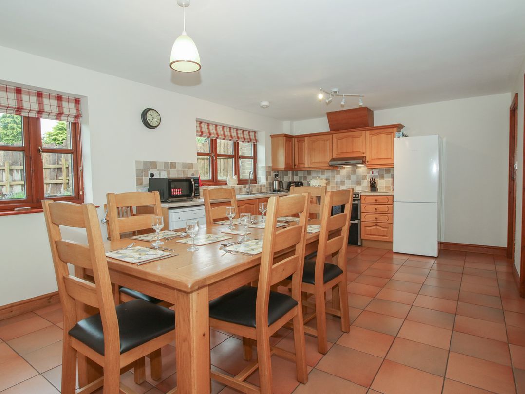 A kitchen with a dining table and appliances at Byne Brook Cottage Strefford near Craven Arms