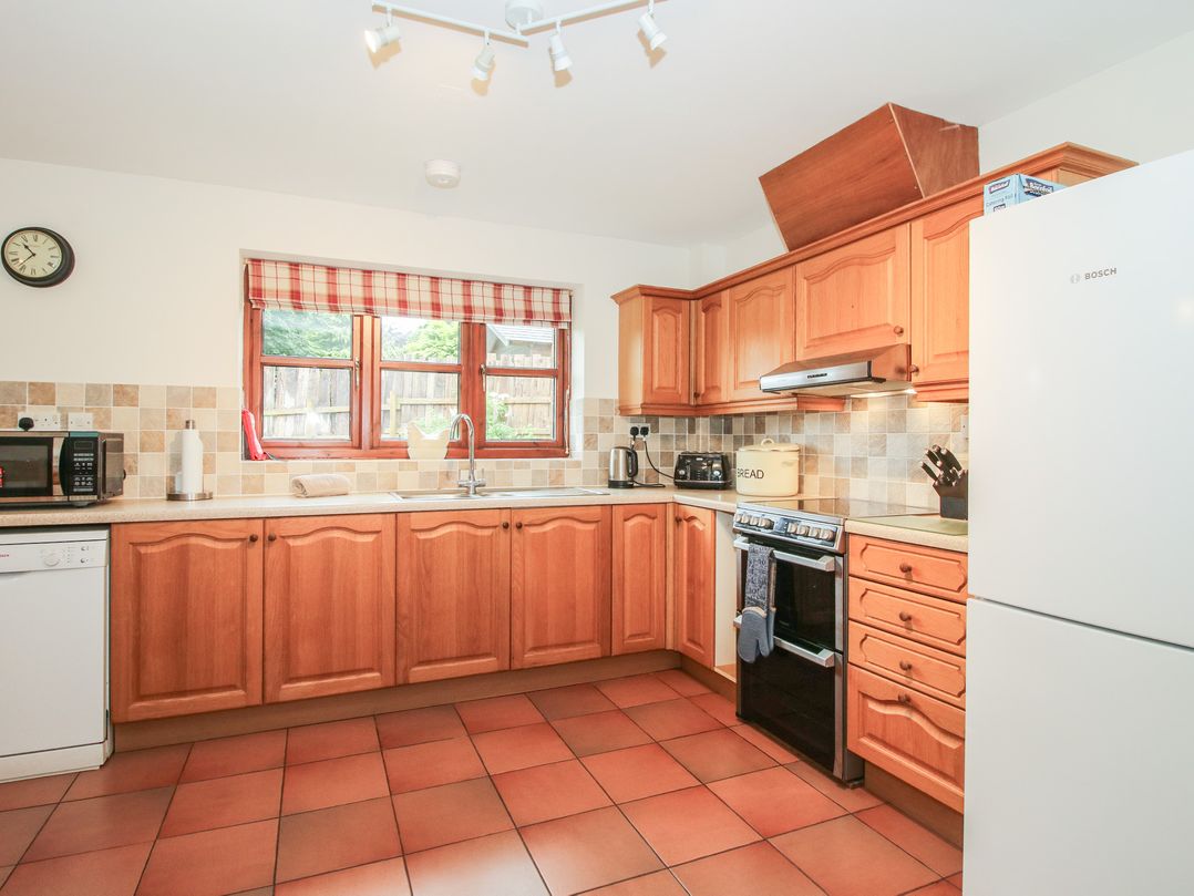 A kitchen with wooden cabinets and appliances at Byne Brook Cottage Strefford near Craven Arms