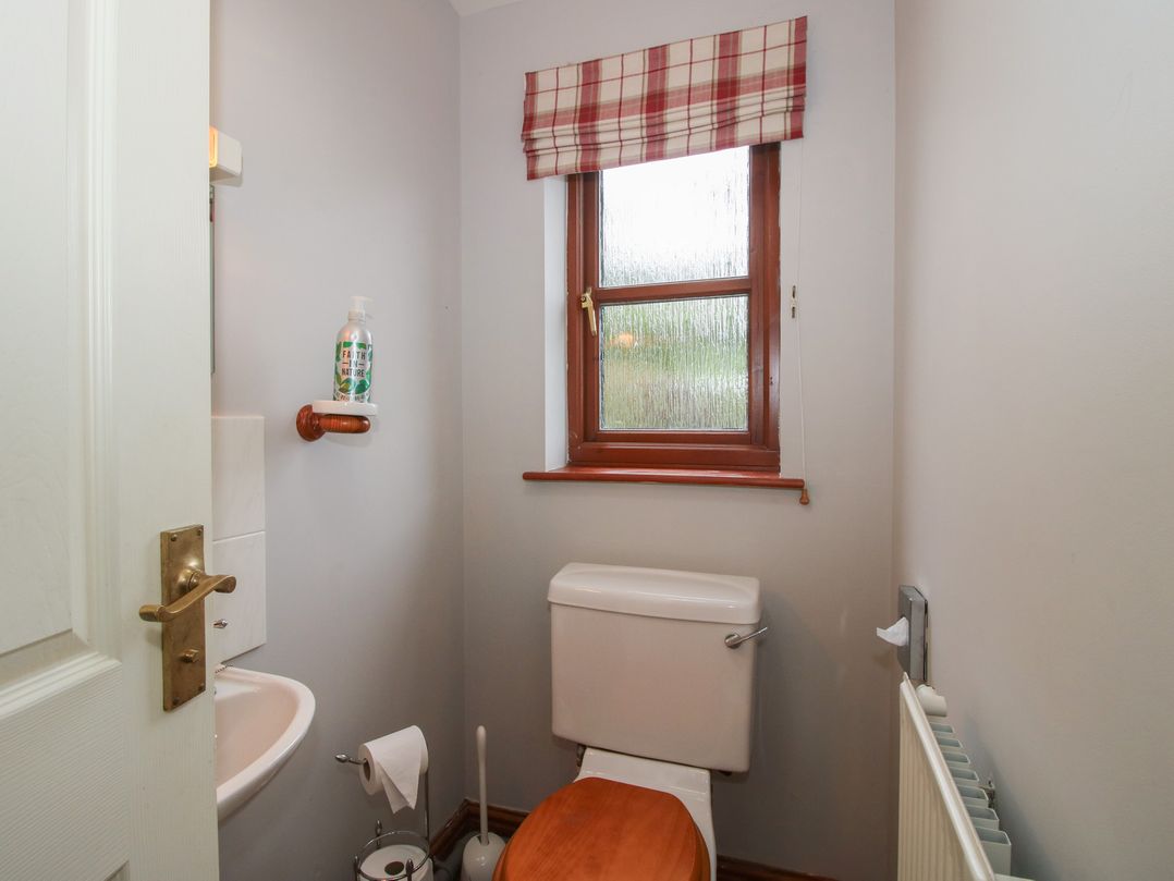 A bathroom with a toilet and sink at Byne Brook Cottage in Strefford near Craven Arms