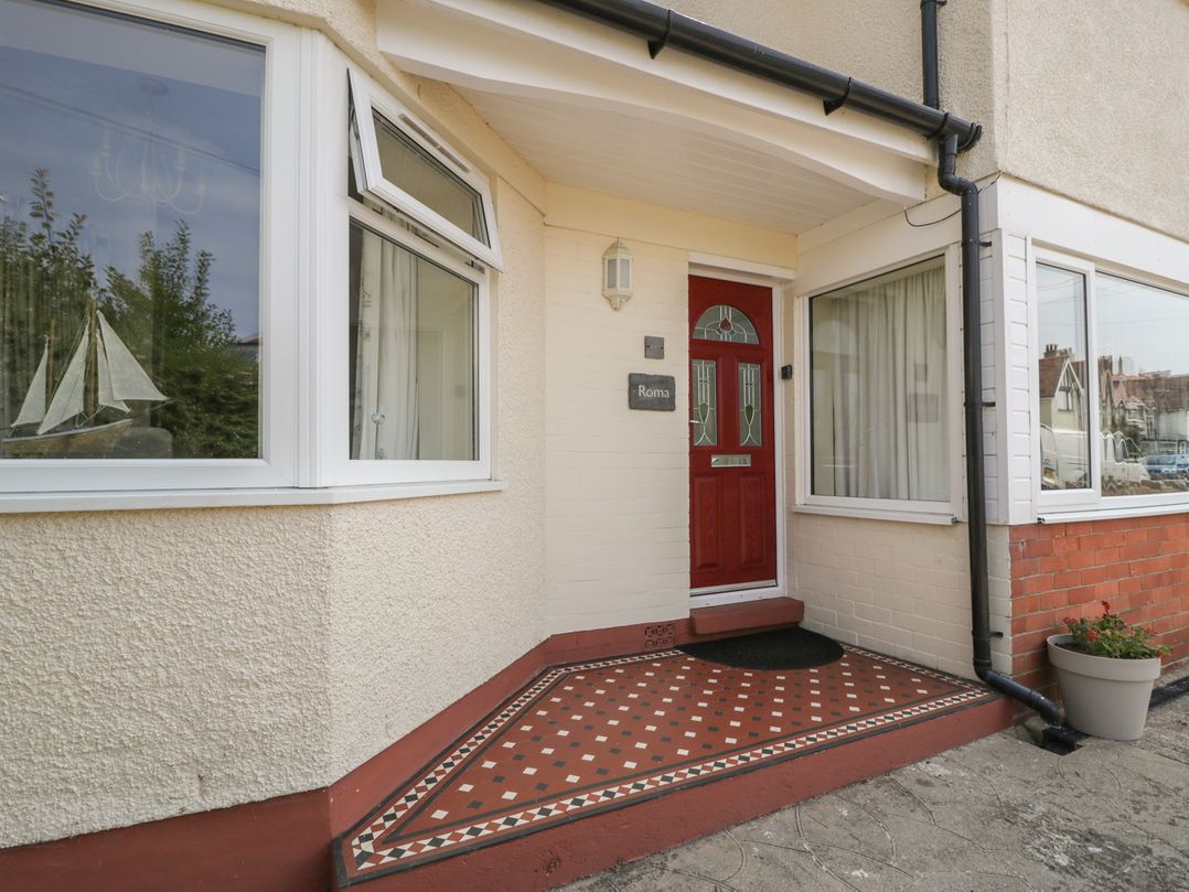 An entrance with a red door and windows at Roma in Rhos-on-Sea