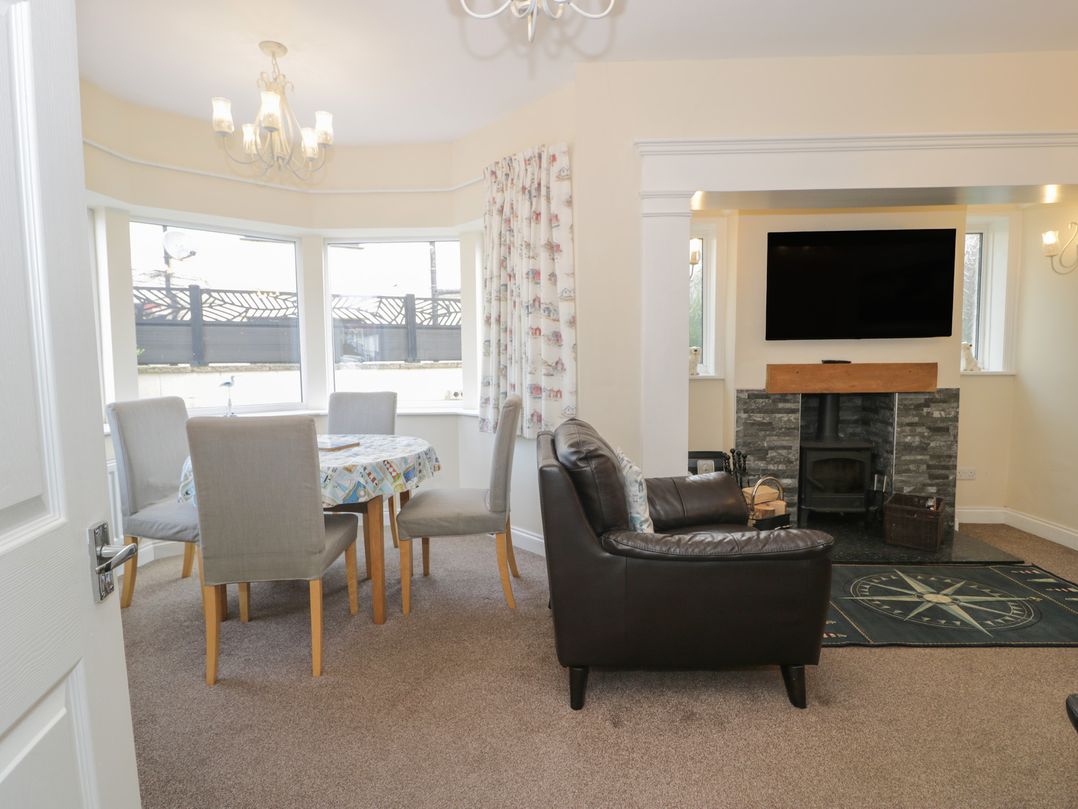 A dining room with a table and chairs and a fireplace at Roma in Rhos-on-Sea