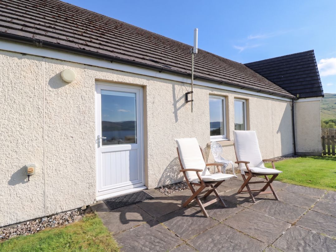 An outdoor area with two chairs and a door at Starfish Cottage, Craignure, Isle Of Mull