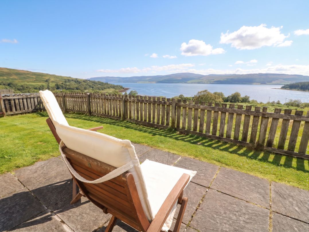 A deck chair with a view of water and hills at Starfish Cottage, Craignure, Isle Of Mull