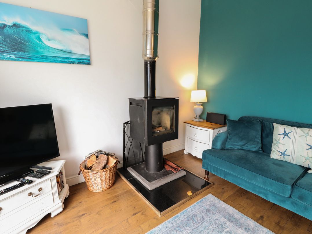 A living room with a wood stove and sofa at Starfish Cottage in Craignure, Isle Of Mull