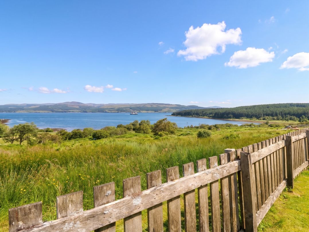 A landscape with a fence overlooking a body of water at Driftwood Cottage Craignure, Isle Of Mull