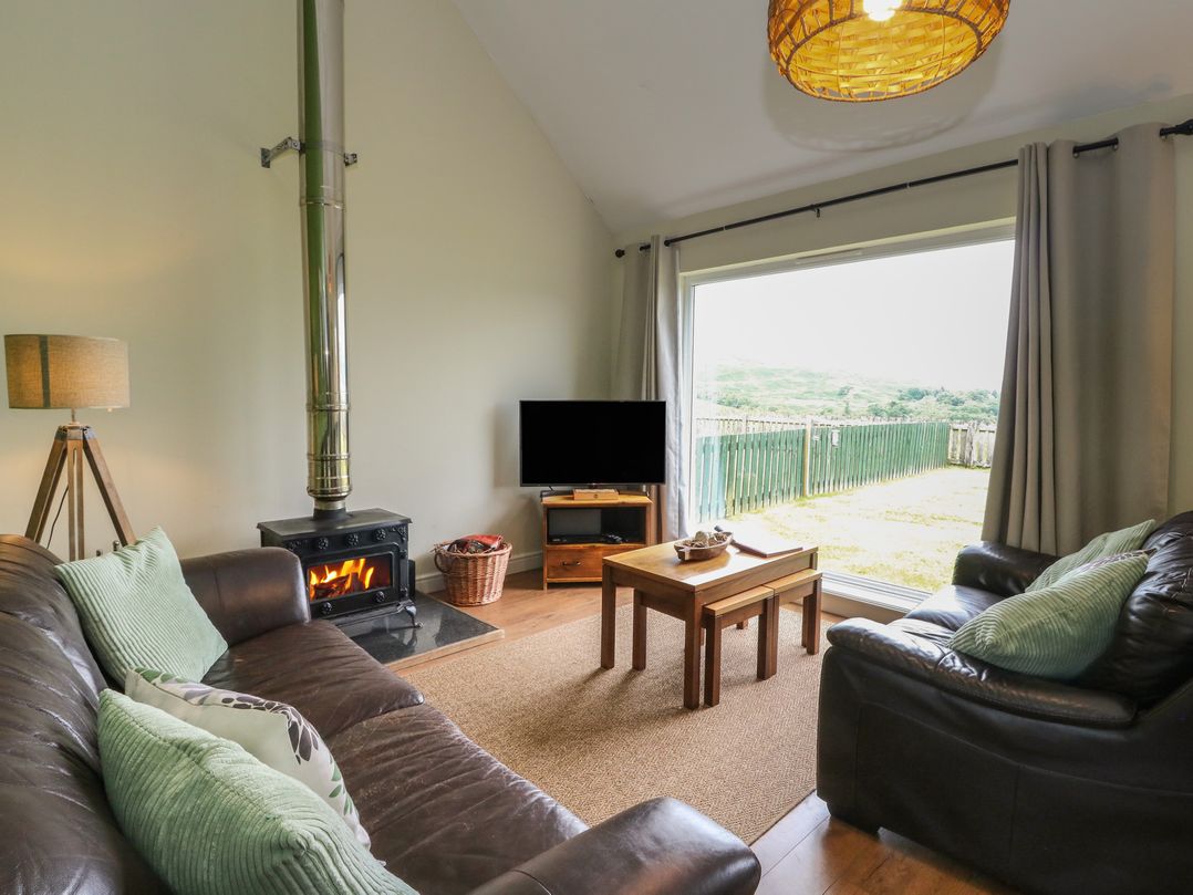 A living room with a television and lamp at Driftwood Cottage in Craignure, Isle Of Mull