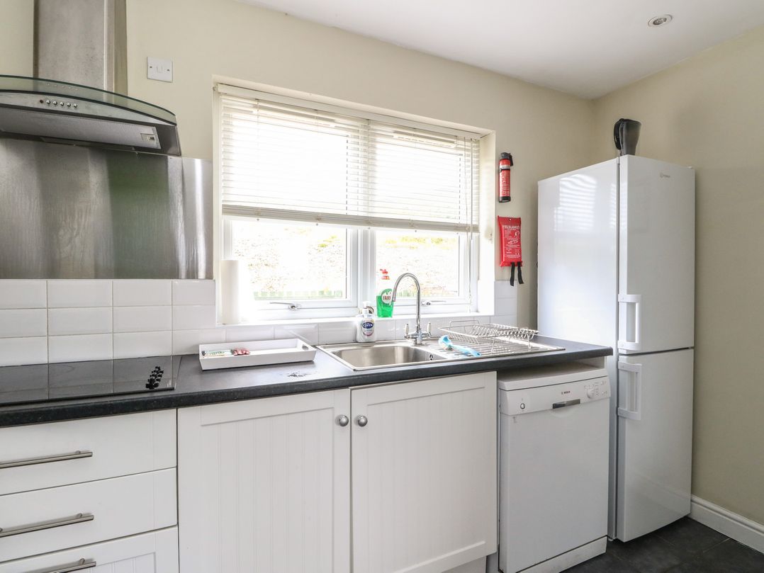 A kitchen with a sink, refrigerator, dishwasher and cabinets at Driftwood Cottage, Craignure, Isle Of Mull