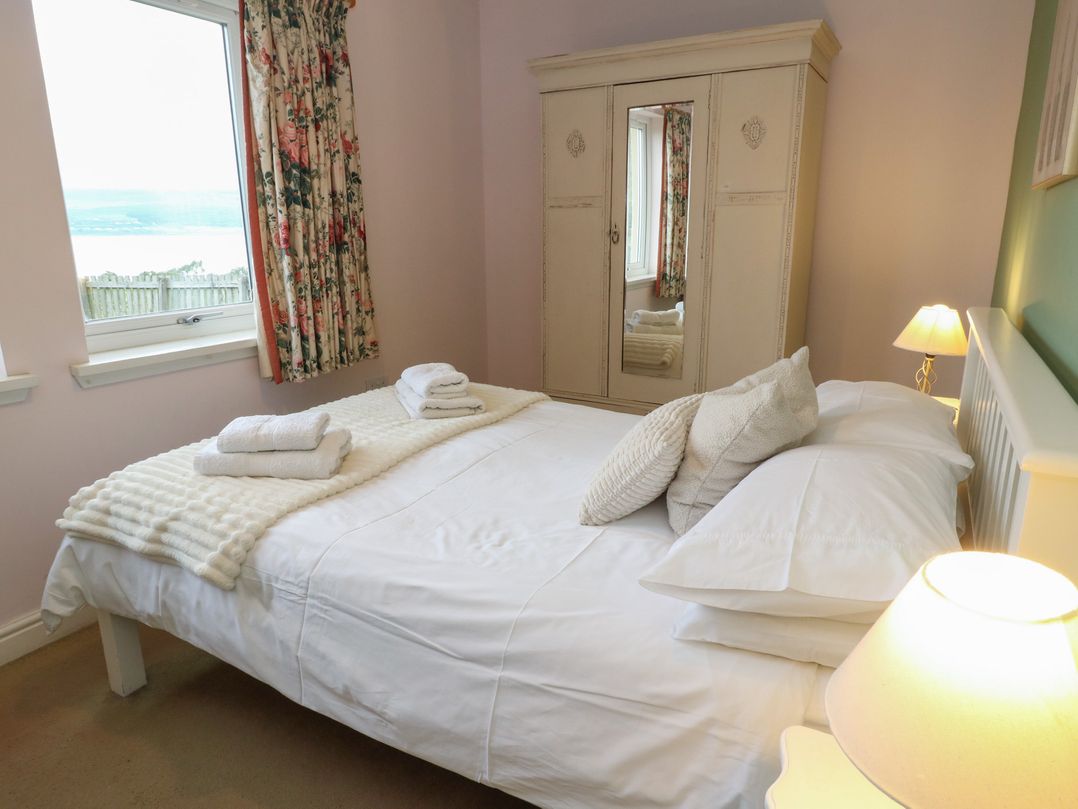 A bedroom with a bed and wardrobe at Driftwood Cottage, Craignure, Isle Of Mull