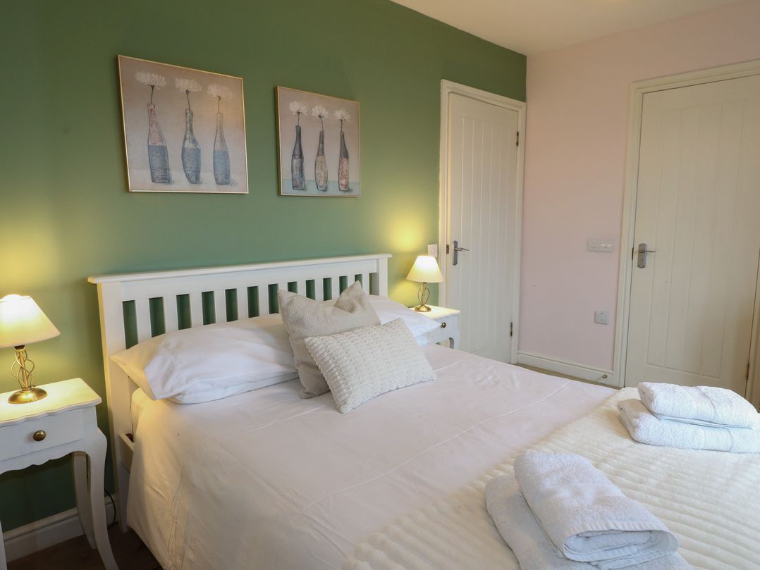 A bedroom with a bed and wall art at Driftwood Cottage, Craignure, Isle Of Mull
