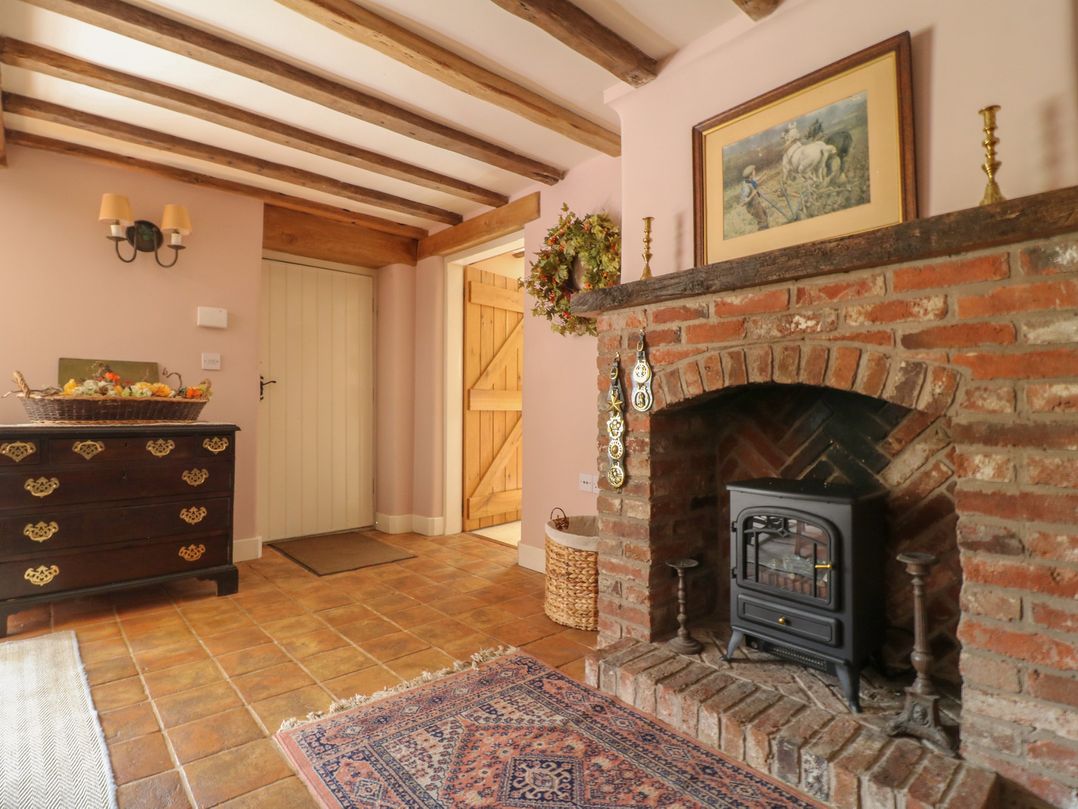 A hallway with a fireplace and a chest of drawers at Just A Cottage, Newlands Farm in Golden Valley near Riddings and Alfreton