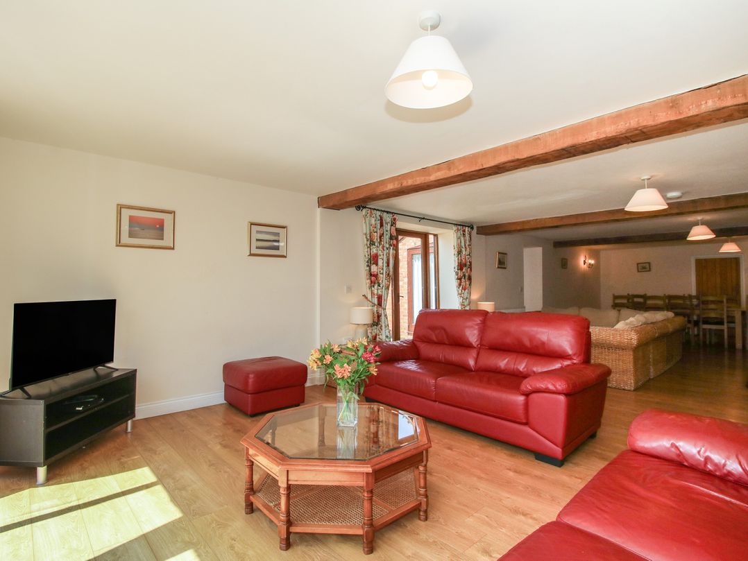 A living room with red sofas and a television at The Wainhouse in Bockleton near Tenbury Wells