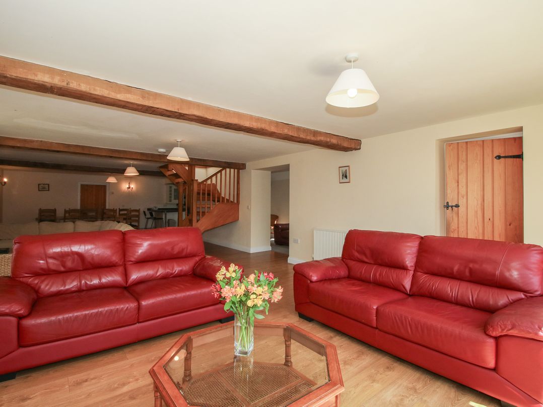 A living room with red sofas and a coffee table at The Wainhouse in Bockleton near Tenbury Wells