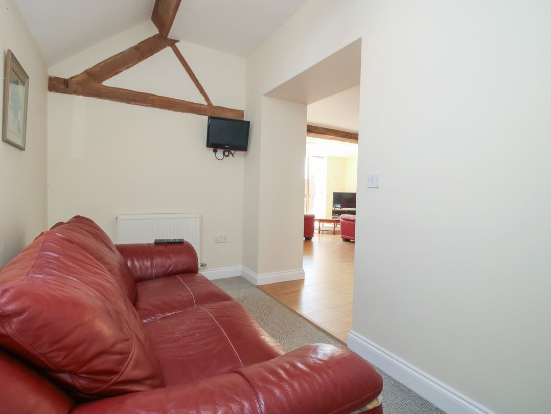 A living room with a red sofa and a television at The Wainhouse in Bockleton near Tenbury Wells