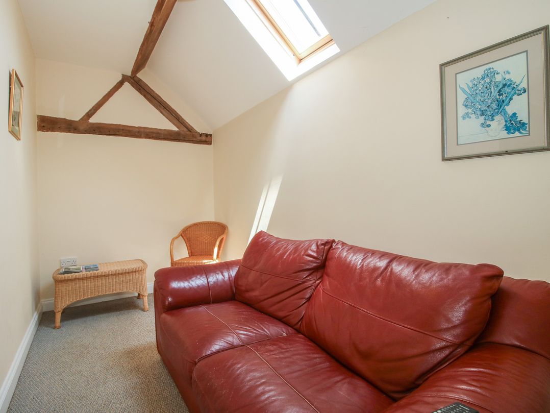 A snug with a red sofa and a wicker chair at The Wainhouse in Bockleton near Tenbury Wells