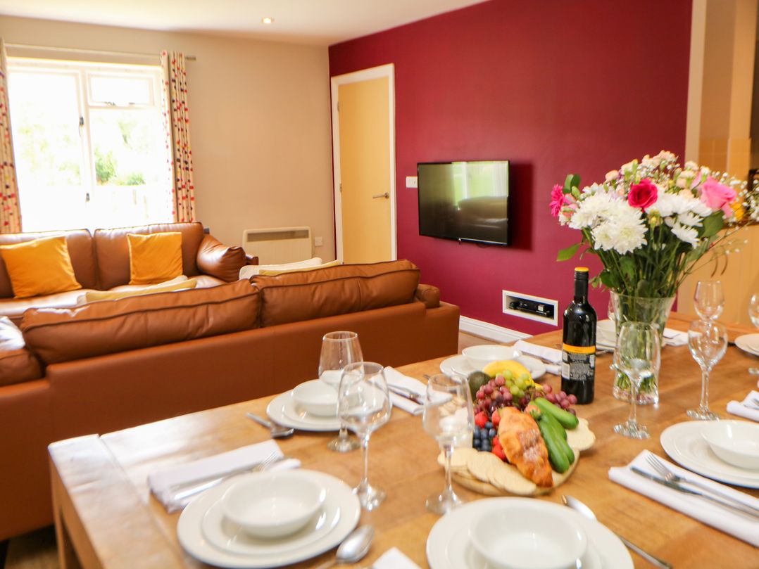 A dining room with a table set for meals and a sofa at Wensley in Matlock