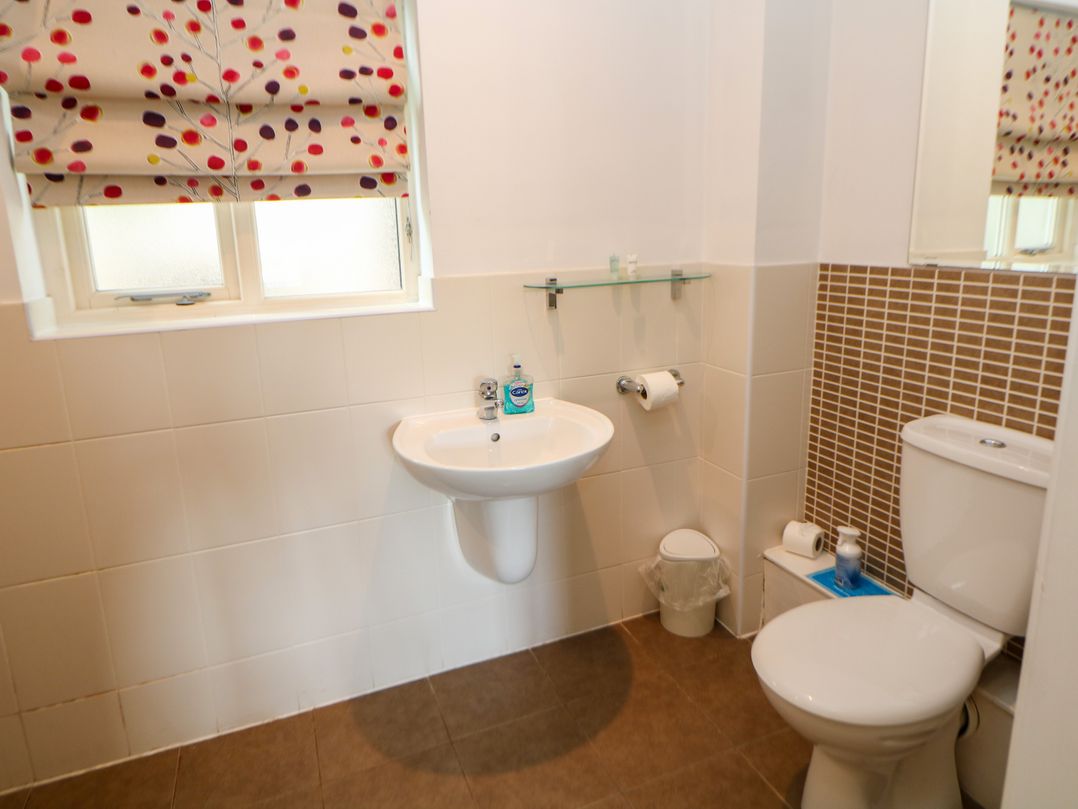 A bathroom with a sink, toilet, and window at Wensley in Matlock