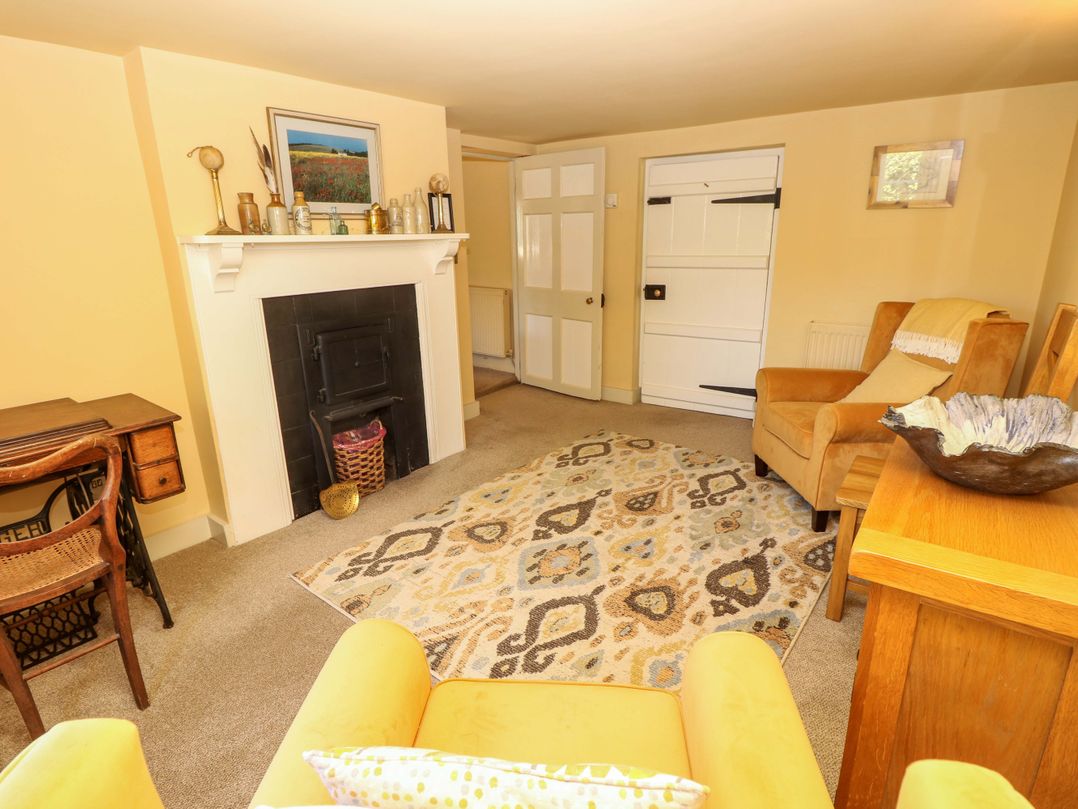 A living room with a fireplace and seating at Sweet Briars in Chale