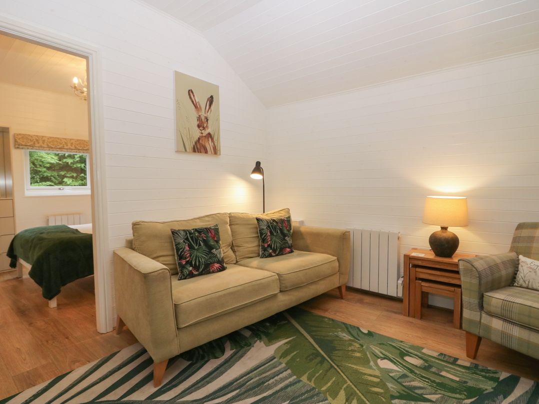 A living room with a sofa and lamp at Ash Lodge in Pennington near Ulverston