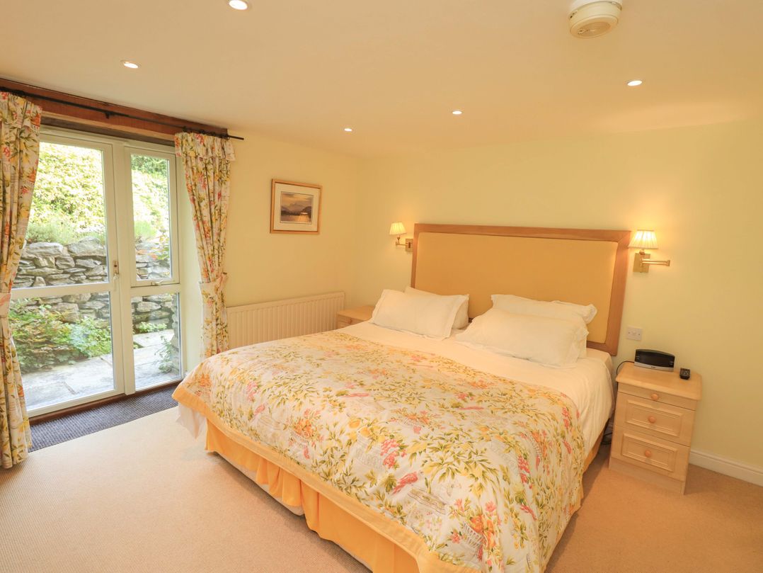 A bedroom with a double bed and windows at Pheasant Cottage near Cartmel
