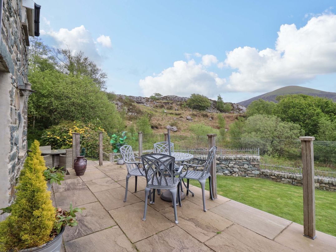 An outdoor terrace with a table and chairs at Moelfre Cottage Llanbedr