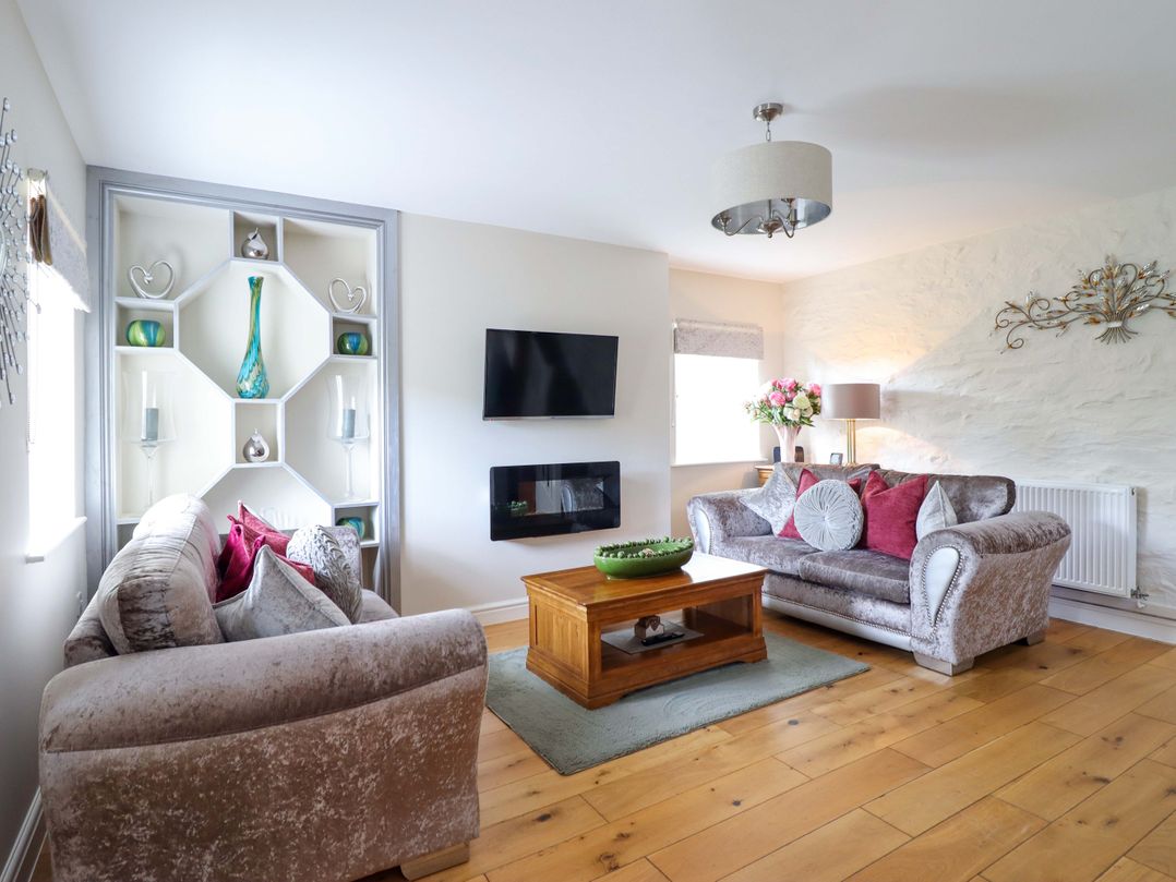 A living room with a sofa, tv, and coffee table at Moelfre Cottage in Llanbedr