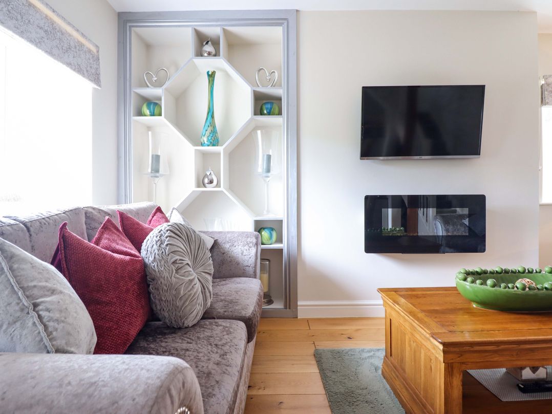 A living room with a sofa and shelves at Moelfre Cottage in Llanbedr