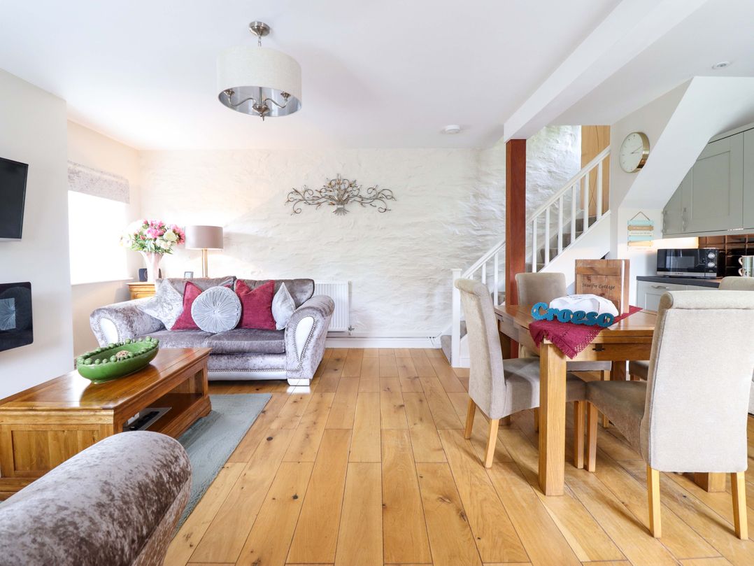 A living room with a sofa and dining area at Moelfre Cottage Llanbedr