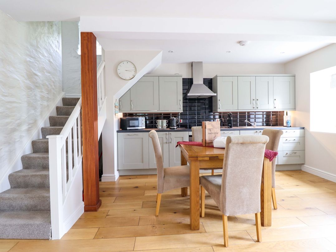 A kitchen with a dining table and chairs at Moelfre Cottage in Llanbedr