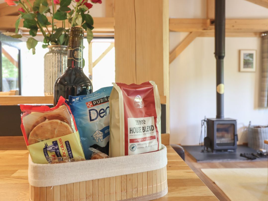A kitchen with a basket of snacks and a wood stove at Lady Bagots Cabin in Ruthin