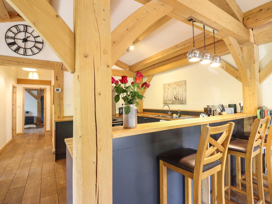 A kitchen with wooden beams and bar stools at Lady Bagots Cabin in Ruthin