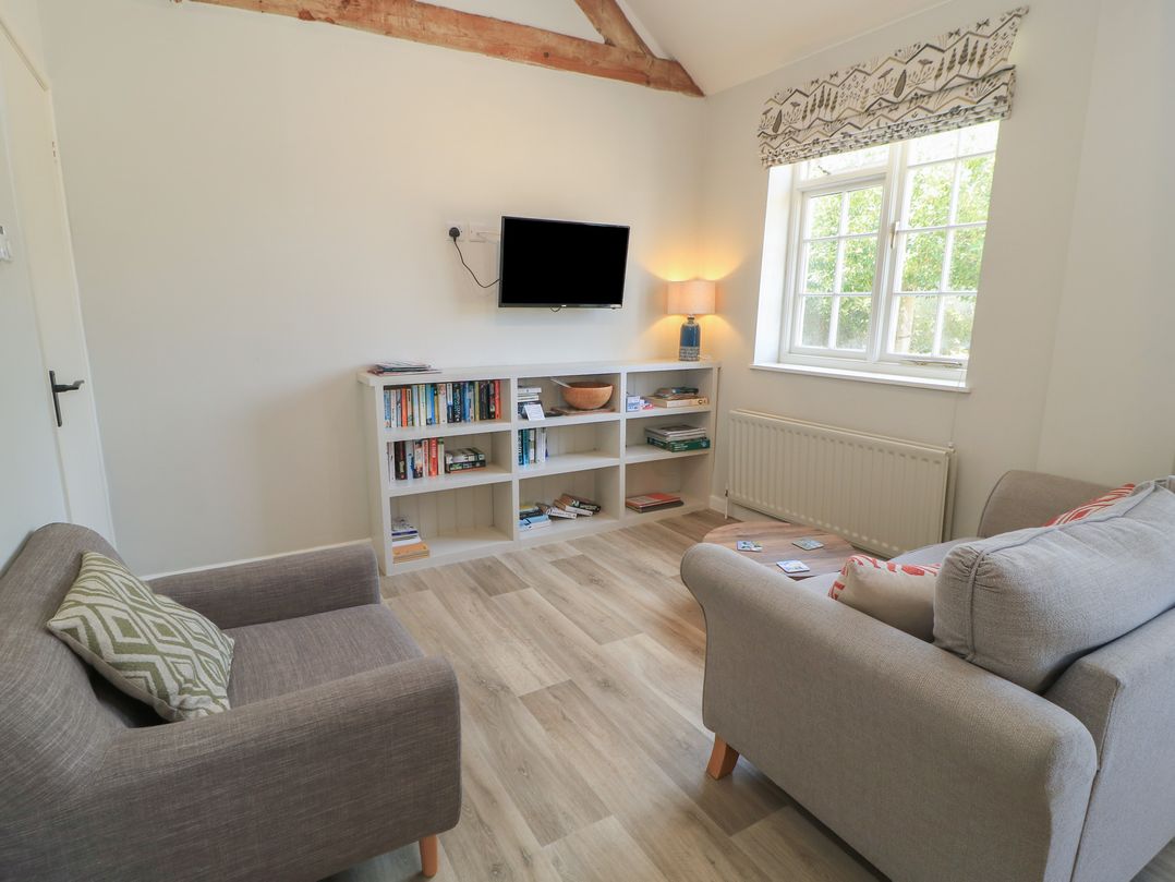 A living room with a television and bookshelves at The Cider Press, Motcombe