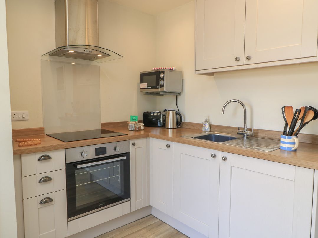 A kitchen with an oven, cooktop, microwave, and sink at The Apple Shed, Motcombe