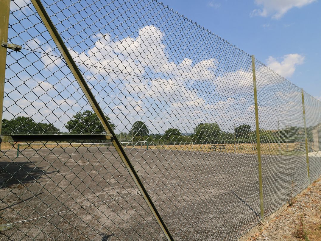 A chain link fence surrounding a paved area at The Apple Shed, Motcombe