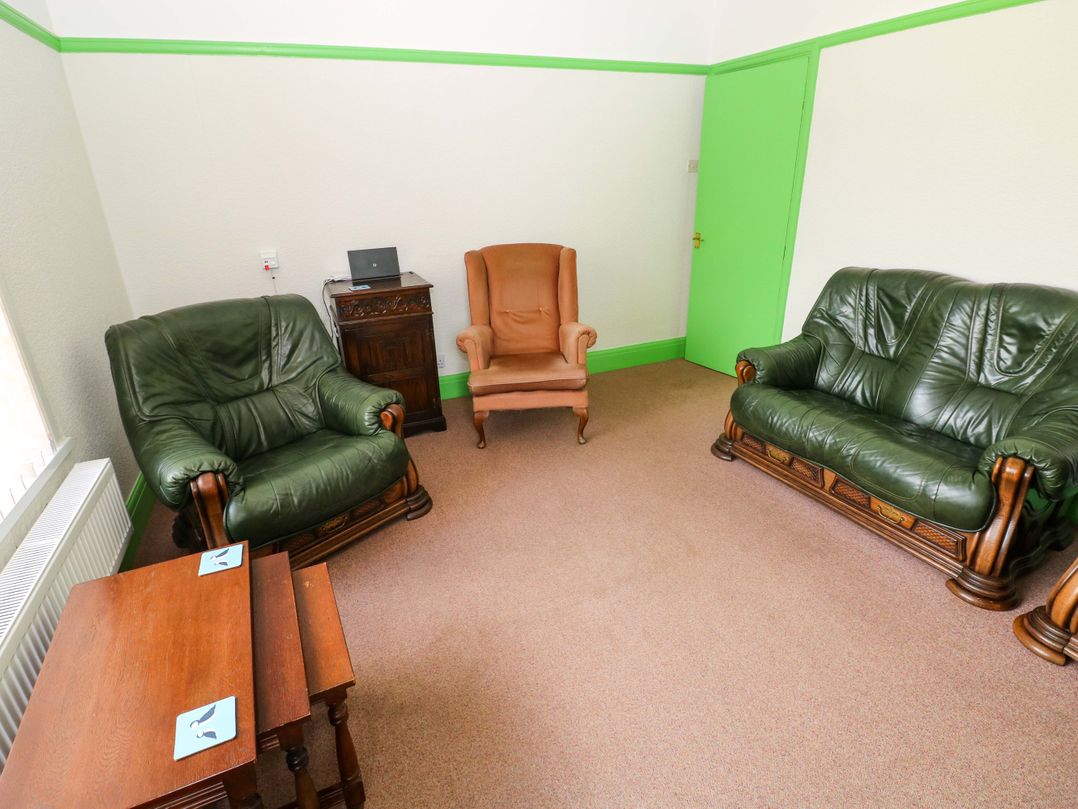 A living room with seating and a laptop at White Thorns in Haverfordwest