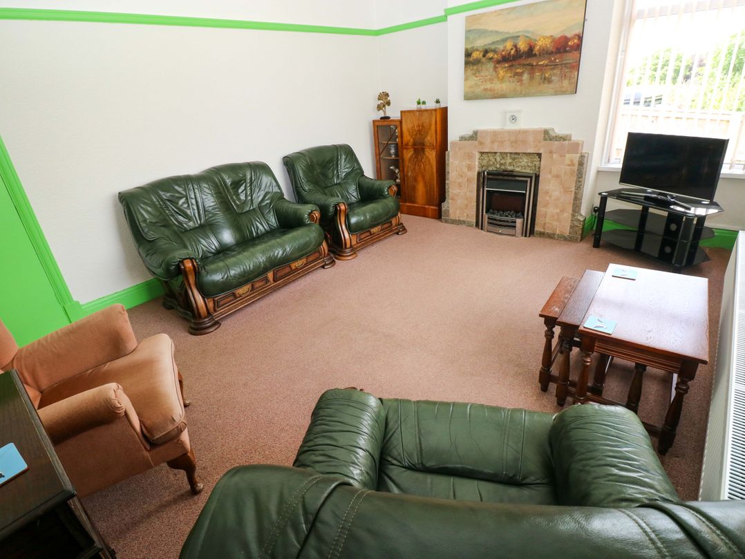 A living room with green sofas and armchair at White Thorns in Haverfordwest