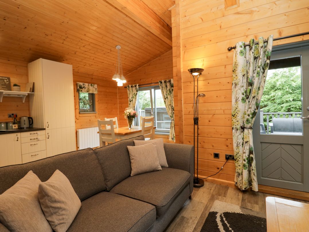 A living room with a sofa and dining area at Elm Lodge in Ulverston