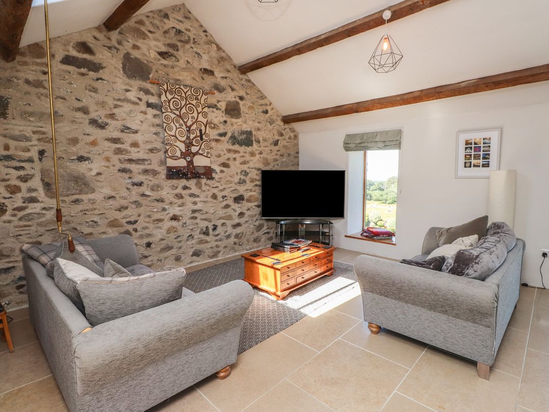 A living room with sofas and a television at Wern Olau Cottage in Groeslon near Caernarfon
