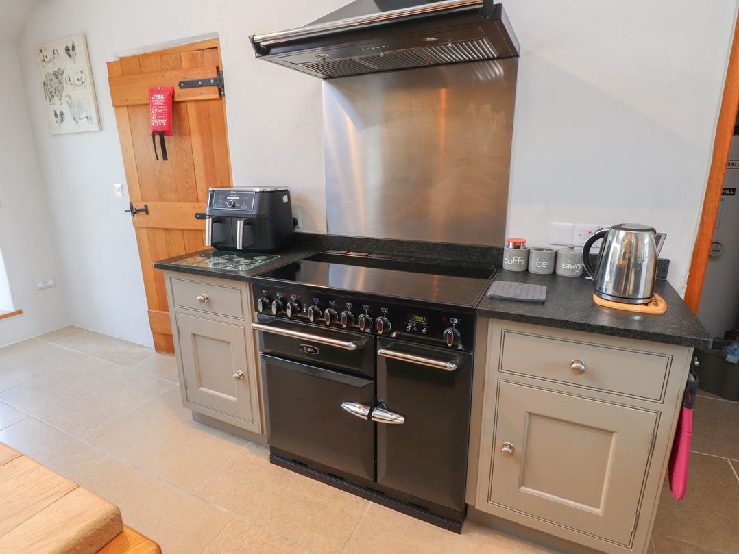 A kitchen with an oven, coffee maker, kettle and kitchen units at Wern Olau Cottage Groeslon near Caernarfon