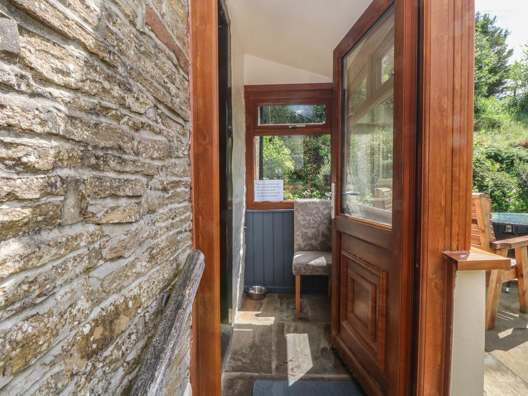 An entrance area with a stone wall and a chair at West End House Thornton, West Yorkshire